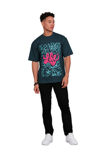 Person wearing a LIFE OVERSIZED T-SHIRT - TEAL GREEN with a pink 'LIFE' design on a white background